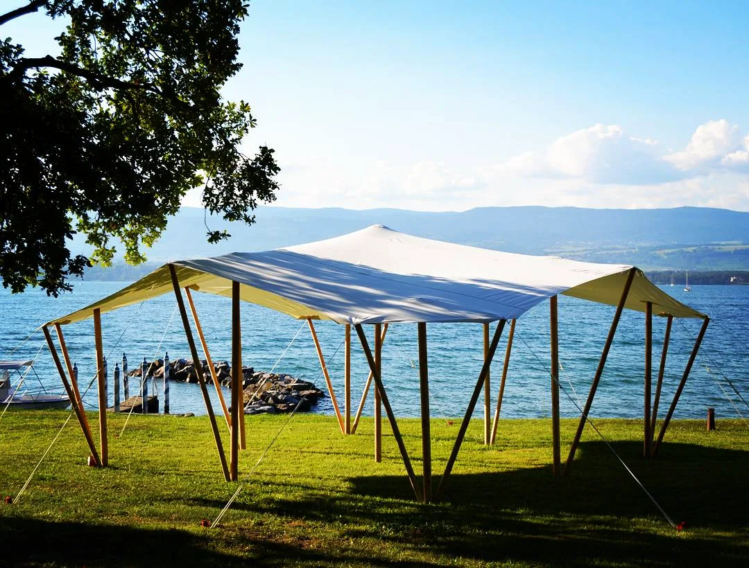 Toile nomade tendue sur ses poteaux de mélèze au bord du lac Léman, montagnes au fond
